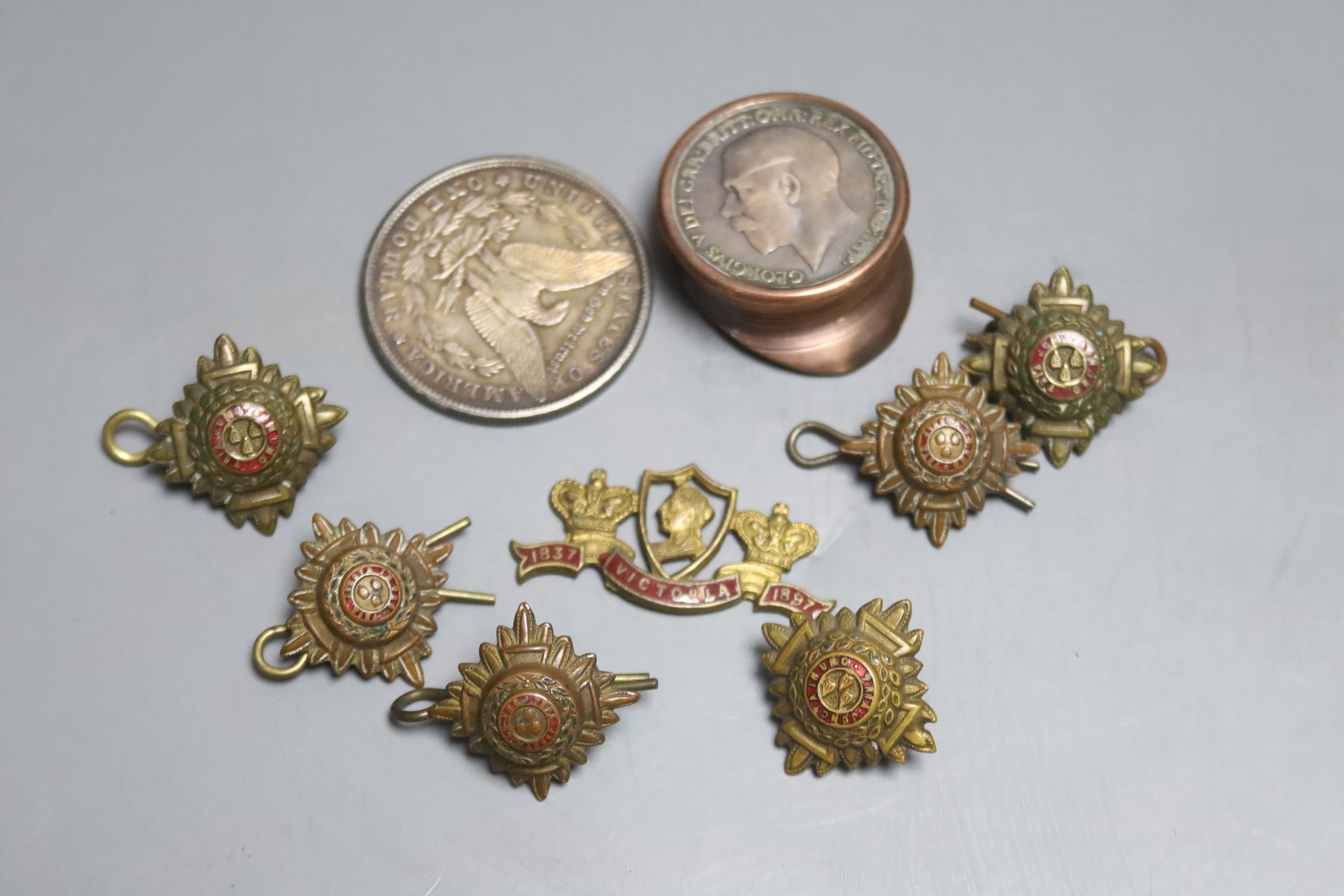 A US silver dollar 1881, five regimental buttons and a badge, copper penny cap